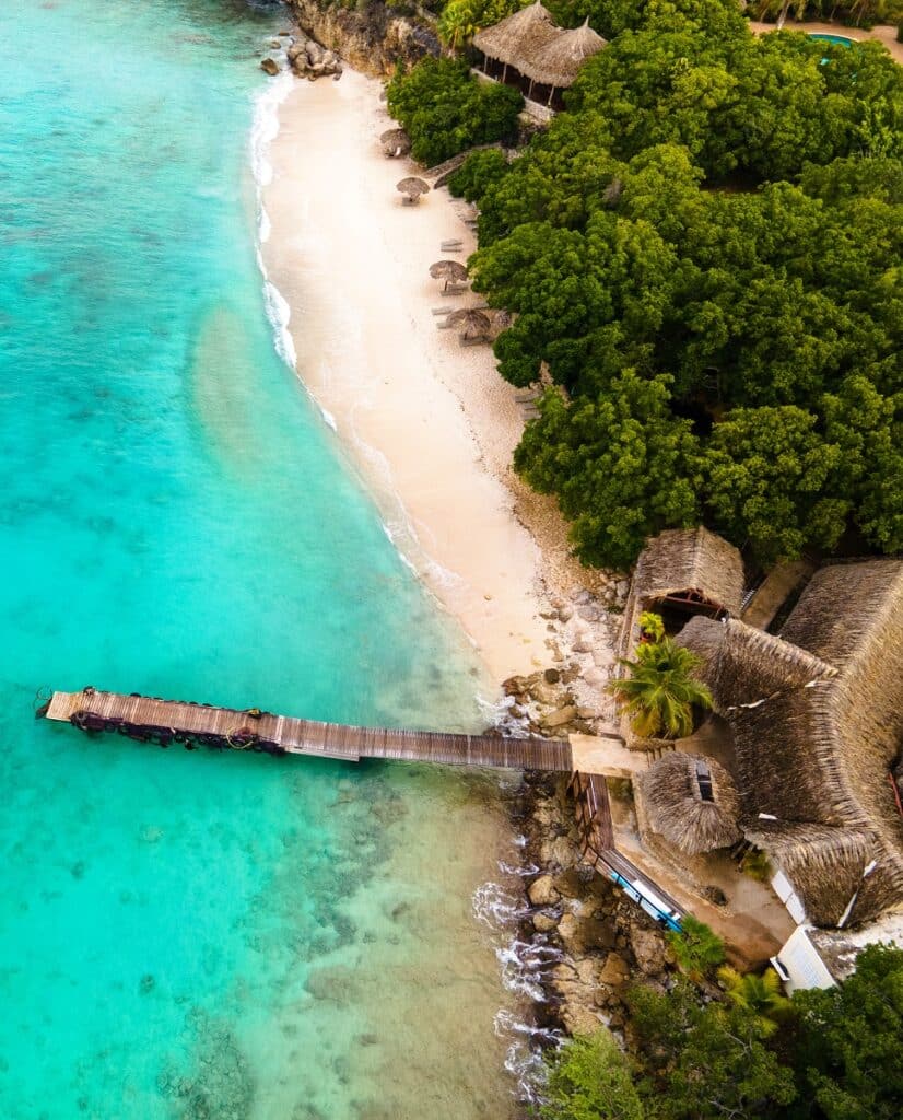 Beach and Pier at playa Kalki in Curacao, tropical beach from the sky drone view at the beach with palm tree Curacao