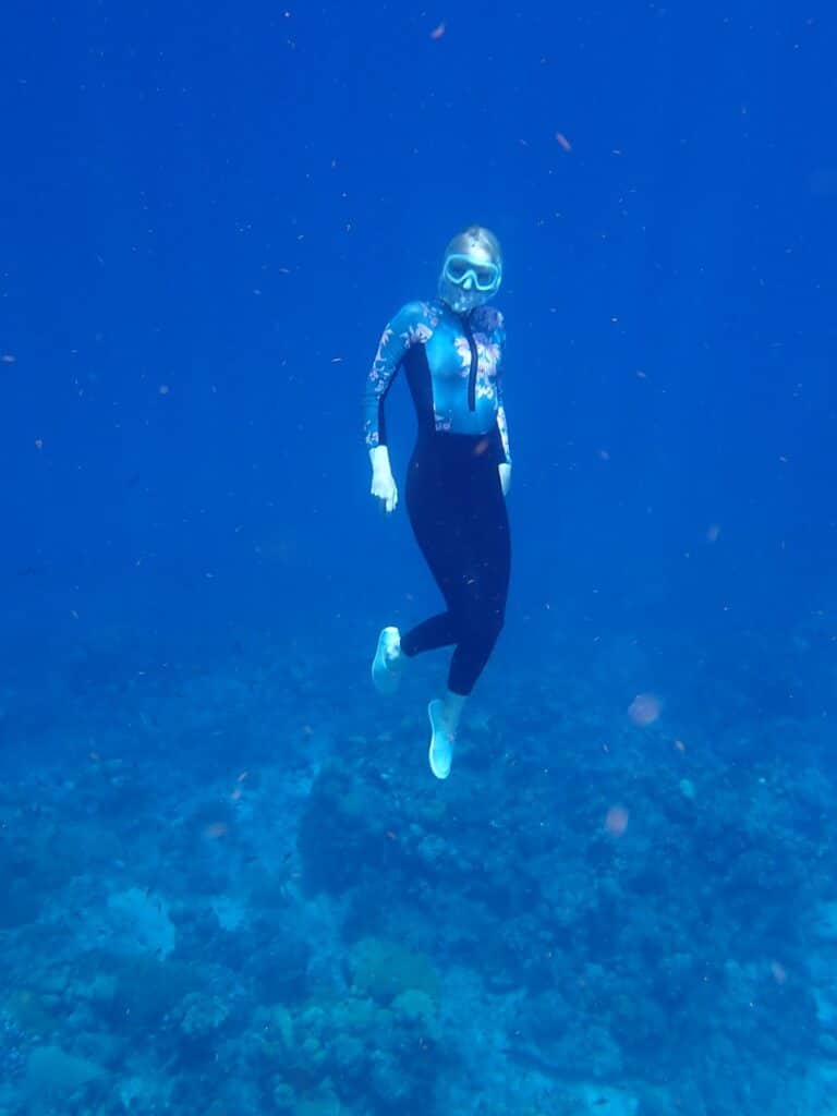 Woman swimming underwater with snorkel and goggles.